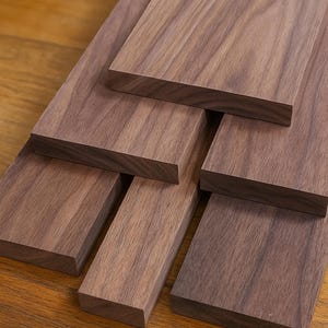May include: A collection of rectangular, unfinished walnut wood planks. The planks vary in size and are arranged in a layered pattern, showcasing the natural grain and rich brown color of the wood. Ideal for woodworking projects.