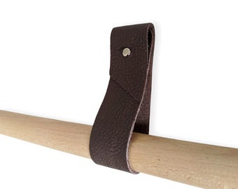 May include: A brown leather strap with a metal rivet, attached to a wooden dowel rod.