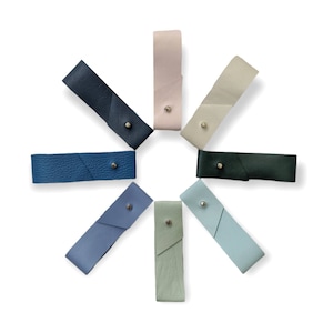 May include: Eight leather straps in different colors arranged in a circle. The straps are all the same size and have a small metal button on one end.