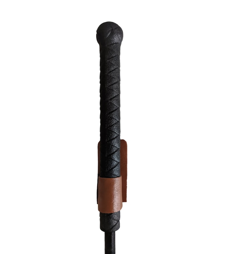 May include: A black leather riding crop with a braided handle and a brown leather strap.