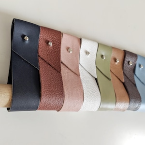 May include: A set of ten leather wristlets in various colors, including black, brown, pink, white, green, and blue. Each wristlet has a silver snap closure.