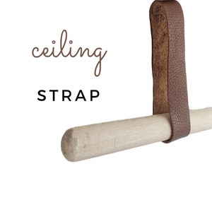 Può includere: Un cinturino in pelle marrone attaccato a un  d'una bacchetta di legno. Il cinturino è etichettato "cinghia per soffitto".