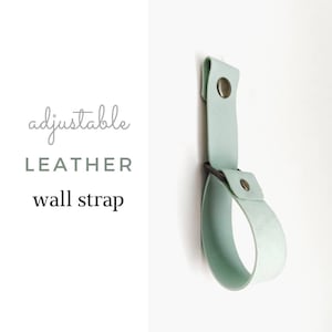 May include: Adjustable leather wall strap in a light green color. The strap has a metal buckle and two metal rivets.