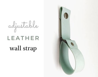 May include: Adjustable leather wall strap in a light green colour. The strap has a metal buckle and two metal rivets.