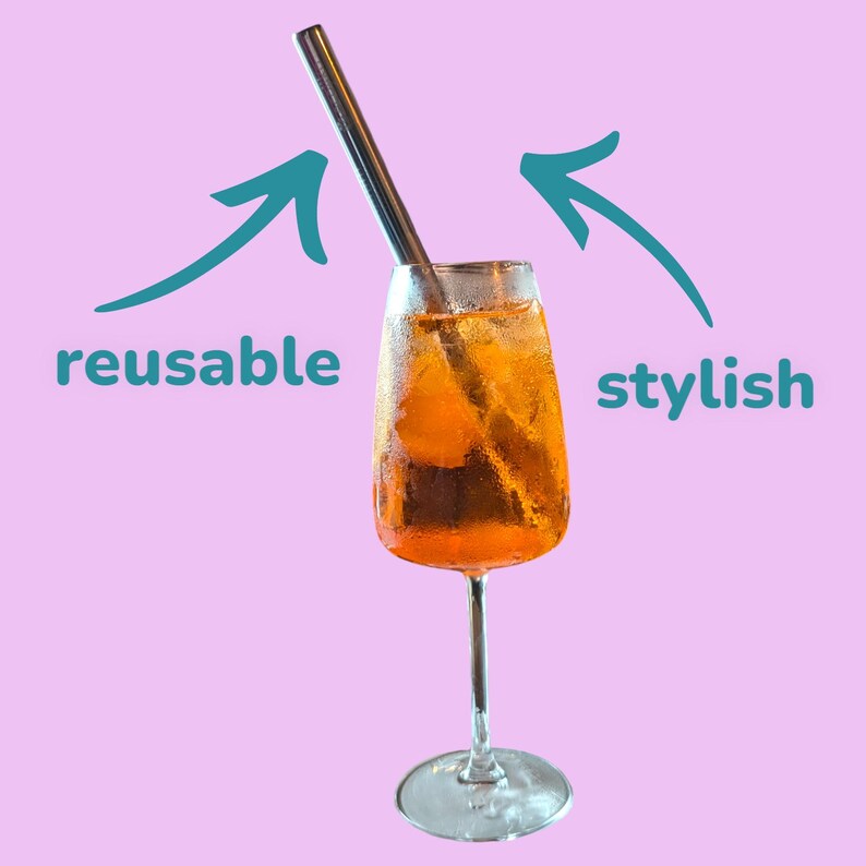 May include: A glass of orange juice with ice and a reusable metal straw. The straw is labeled "reusable" and the drink is labeled "stylish".