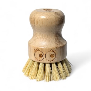 May include: A wooden dish brush with a bamboo handle and natural bristles. The handle has a cute face with eyes and eyelashes.
