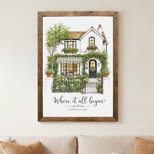 May include: A framed watercolor-style print of a two-story house with green climbing vines, a striped awning, and a dark front door. The text "Where it all began" is printed below the house illustration, followed by the date "MARCH 12, 2024".