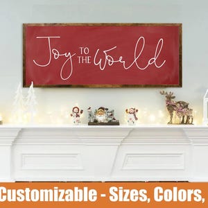 May include: A red framed sign with the words "Joy to the World" in white script. The sign is above a white mantel decorated with Christmas figurines, lights, and a red ornament. The text "Fully Customizable - Sizes, Colors, Fonts" is at the bottom.