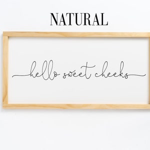 K&ouml;nnte beinhalten: Ein gerahmtes Holzschild mit dem Text "hello sweet cheeks" in schwarzer Kursivschrift.