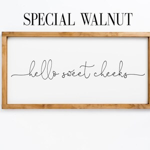 K&ouml;nnte beinhalten: Ein Schild in einem Holzrahmen mit dem Text "hello sweet cheeks" in einer kursivschrift.