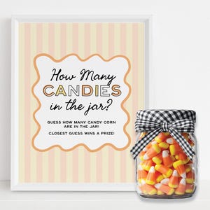 Op de afbeelding: Een ingelijst bord met de tekst "How Many CANDIES in the jar?" naast een glazen pot gevuld met snoepmaïs. Het bord heeft een perzik- en wit gestreepte achtergrond en een decoratieve rand. De pot is afgewerkt met een zwart-wit geruite strik.