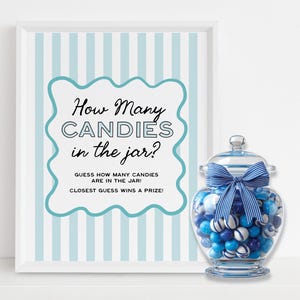 Op de afbeelding: Een ingelijst bord met de tekst "How Many Candies in the Jar?" naast een glazen pot gevuld met blauwe en witte snoepjes. De pot heeft een blauw lint om het deksel gebonden. Het bord heeft een lichtblauwe gestreepte achtergrond.