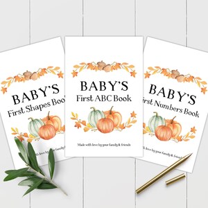 Peut inclure: Trois couvertures de livres imprimables sur le thème de l'automne. Les couvertures présentent une couronne de feuilles d'automne, de glands et de citrouilles. Le texte sur les couvertures est "Baby's First Shapes Book", "Baby's First ABC Book" et "Baby's First Numbers Book".