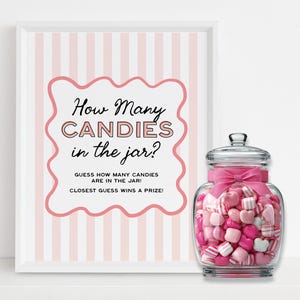 Op de afbeelding: Een ingelijst bord met roze en witte strepen en de tekst "How Many CANDIES in the jar?" naast een glazen pot gevuld met roze en witte snoepjes. De pot heeft een roze strik eromheen.