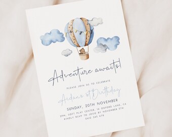 Puede incluir: Un globo aerostático azul y marrón con un osito de peluche dentro, rodeado de nubes blancas. El texto "Adventure awaits!" está escrito en cursiva sobre el globo. El texto "Please join us to celebrate Aidan's 1st Birthday" está escrito debajo del globo. El texto "Sunday, 20th November" está escrito debajo del texto "Aidan's 1st Birthday". El texto "2pm, Soft Play Center, 14 Oxford Lane, CA" está escrito debajo del texto "Sunday, 20th November". El texto "Kindly RSVP to Josie by November 5th" está escrito debajo del texto "2pm, Soft Play Center, 14 Oxford Lane, CA". El texto "0412 345 678" está escrito debajo del texto "Kindly RSVP to Josie by November 5th".