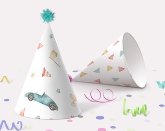 May include: Two party hats with different patterns. One hat is white with blue cars, stars, and flags. The other hat is white with a pattern of colorful triangles. Both hats have a white pom-pom on top.