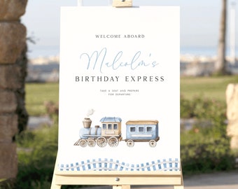 May include: A white sign with blue and brown accents announcing "Welcome Aboard Malcolm's Birthday Express".  The sign features a watercolor illustration of a blue train with white smoke.