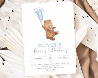 Op de afbeelding: Een blauwe en witte uitnodigingskaart met een bruine beer die een blauwe ballon in de vorm van het nummer één vasthoudt. De tekst op de kaart luidt "Join us for Oliver's Bear-y first birthday, Zaterdag 15 mei 2023, 13:00 - 15:00 uur, Oliver's House, 60 Seabright Avenue, Santa Cruz, Californië, 95062-3422, Graag RSVP aan Sally vóór 29 april, 0412 345 678."