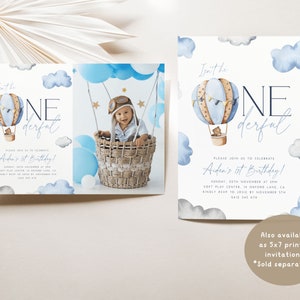Op de afbeelding: Een blauwe en bruine luchtballon met een teddybeer erin, omringd door witte wolken. De tekst "Isn't he one-derful" is in zwart en wit geschreven. De tekst "Aidan's 1st Birthday!" is in paars geschreven. De uitnodiging is voor een eerste verjaardag.