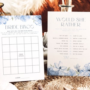 Op de afbeelding: Een printbaar bruidsdouchespel met een blauw bloemenontwerp. Het spel heet "Bride Bingo" en vraagt ​​gasten om te raden welke cadeaus de bruid-in-spe zal ontvangen. Het tweede spel heet "Would She Rather" en vraagt ​​gasten om te kiezen tussen twee opties voor de bruid.