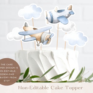 May include: Non-editable cake topper featuring two blue and brown airplanes with white clouds. The cake topper is perfect for a baby shower or birthday party.