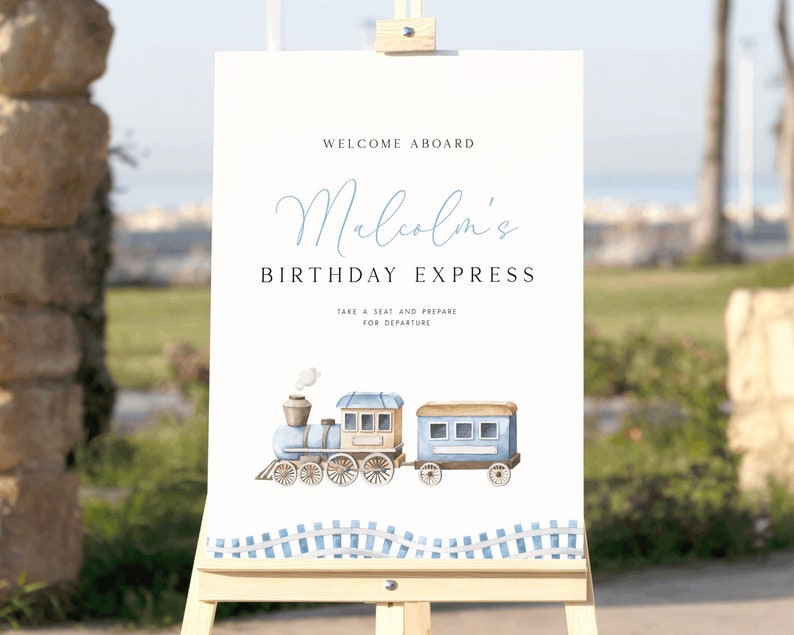 Peut inclure: Une pancarte blanche avec des accents bleus et bruns annon&ccedil;ant "Bienvenue &agrave; bord de l'Express d'anniversaire de Malcolm". La pancarte pr&eacute;sente une illustration aquarelle d'un train bleu avec de la fum&eacute;e blanche.