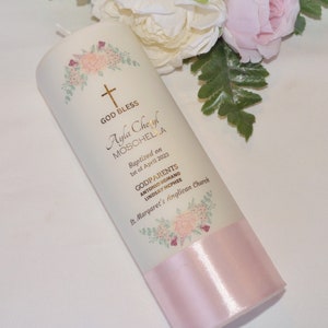 Peut inclure: Bougie de baptême blanche avec un ruban rose et un motif floral. La bougie est décorée d'une inscription dorée qui dit "God Bless Ayla Cheryl Moschella Baptized on 1st of April 2023 Godparents Antonio Romano Lindsay McPhee St. Margaret's Anglican Church."