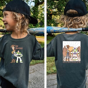 May include: Dark grey t-shirt with a cartoon graphic of Woody and Buzz Lightyear and the text "Big Brother" on the front. The back of the shirt has a matching graphic with the text "You've Got a Friend in Me".