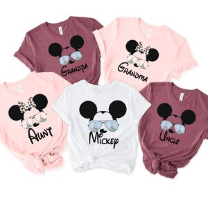 K&ouml;nnte beinhalten: F&uuml;nf T-Shirts mit einem Mickey-Mouse-Motiv. Jedes Shirt tr&auml;gt eine andere Rolle: Tante, Onkel, Oma, Opa und Mickey. Die Shirts sind in Rosa, Wei&szlig; und Rotbraun.