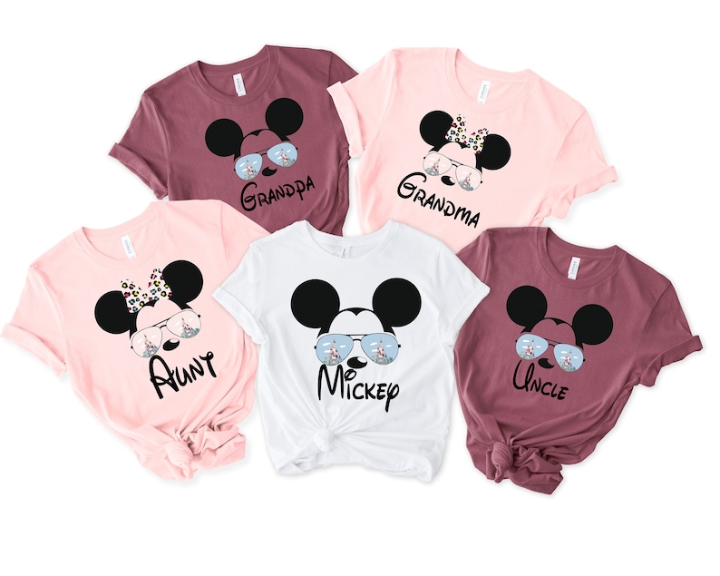 K&ouml;nnte beinhalten: F&uuml;nf T-Shirts mit einem Mickey-Mouse-Motiv. Jedes Shirt tr&auml;gt eine andere Rolle: Tante, Onkel, Oma, Opa und Mickey. Die Shirts sind in Rosa, Wei&szlig; und Rotbraun.