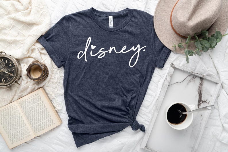 May include: A navy blue t-shirt with the word "disney" written in white cursive with a small heart on the "i".