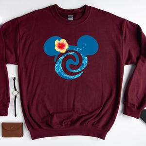 Puede incluir: Sudadera color burdeos con un dise&ntilde;o de cabeza de Mickey Mouse azul y turquesa. La cabeza de Mickey Mouse tiene una flor amarilla en la parte superior.