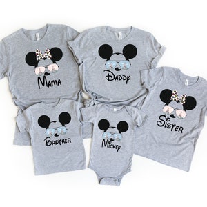 K&ouml;nnte beinhalten: Ein Set aus f&uuml;nf grauen T-Shirts mit einem Cartoon von Mickey Mouse, der eine Sonnenbrille tr&auml;gt, mit einem anderen Wort auf jedem Shirt: Mama, Papa, Schwester, Bruder, Mickey.