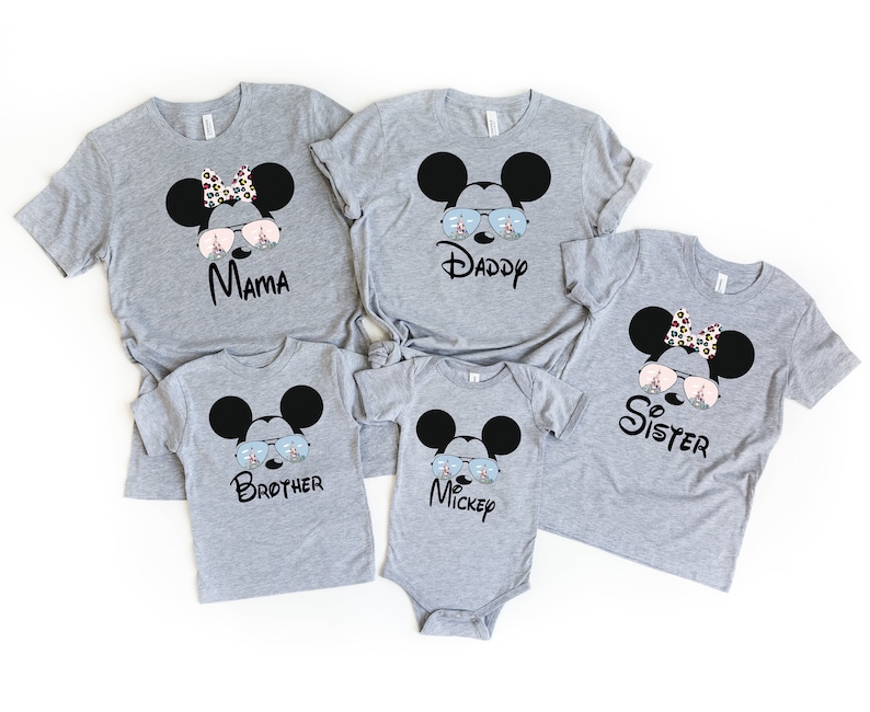 K&ouml;nnte beinhalten: Ein Set aus f&uuml;nf grauen T-Shirts mit einem Cartoon von Mickey Mouse, der eine Sonnenbrille tr&auml;gt, mit einem anderen Wort auf jedem Shirt: Mama, Papa, Schwester, Bruder, Mickey.