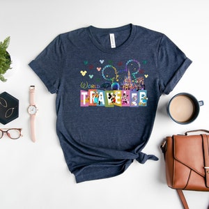 May include: A navy blue t-shirt with a colorful graphic of the Disney World castle, fireworks, and Mickey Mouse characters. The text "World Traveler" is printed on the shirt.