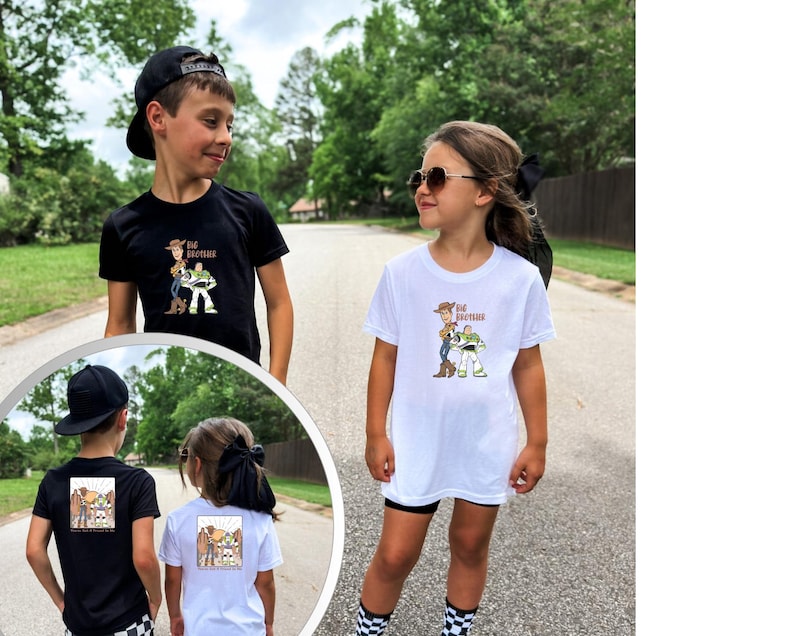 May include: Two children wearing black and white t-shirts featuring a cartoon graphic of Woody and Buzz Lightyear from Toy Story. The shirts have the text "Big Brother" on the front. The children are standing on a paved road.