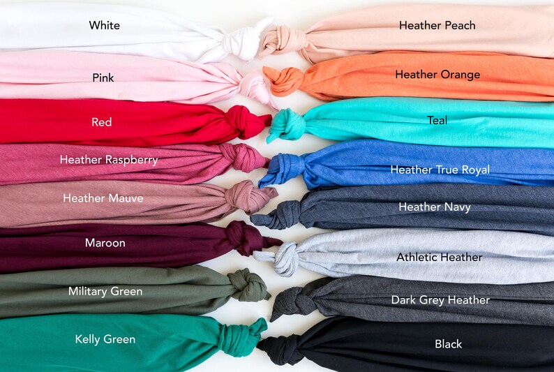 May include: A collection of fabric swatches in various colors, including white, pink, red, heather raspberry, heather mauve, maroon, military green, kelly green, heather peach, heather orange, teal, heather true royal, heather navy, athletic heather, dark grey heather, and black.