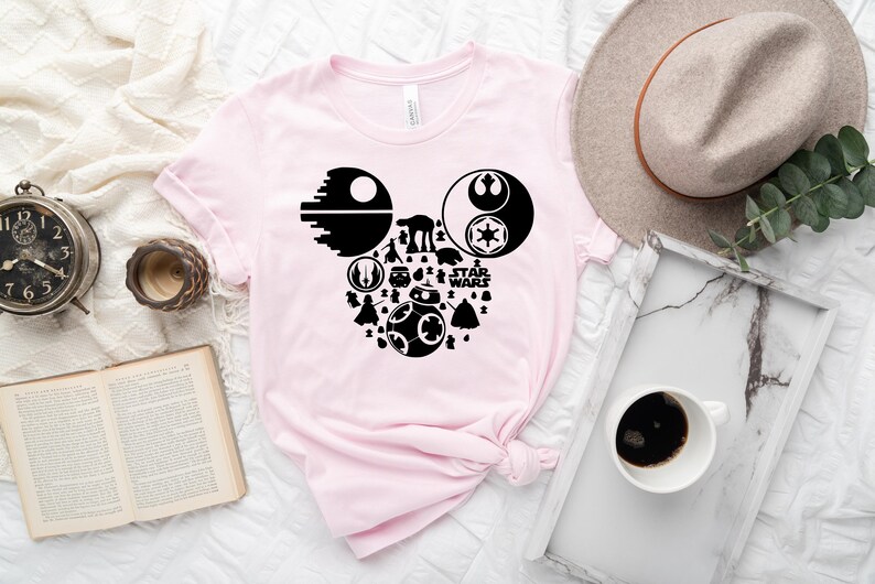 May include: A pink t-shirt with a black Mickey Mouse silhouette design featuring Star Wars characters and the text "Star Wars".