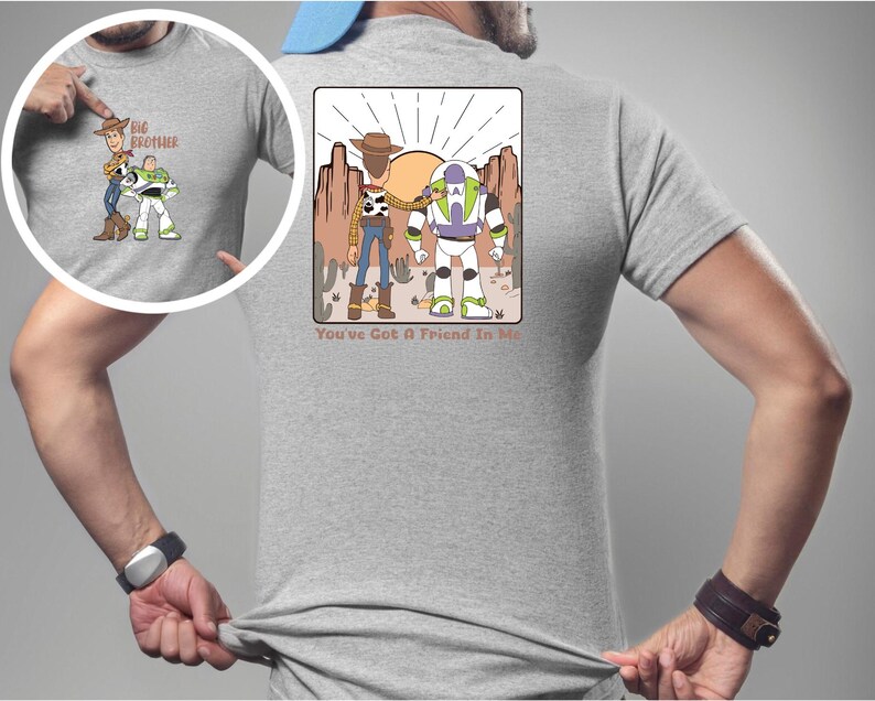 May include: A light grey t-shirt with a cartoon graphic of Woody and Buzz Lightyear in a desert scene. The text "You've Got A Friend In Me" is below the graphic. The shirt also has a smaller graphic on the front with the text "Big Brother".