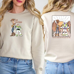 May include: Beige sweatshirt with a cartoon graphic of two characters on the front, and the text "Big Brother". The back features a desert scene with two characters and the text "You've Got A Friend In Me".