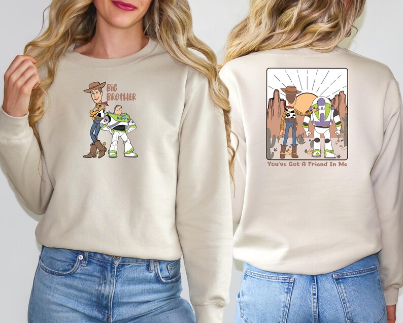 May include: Beige sweatshirt with a cartoon graphic of two characters on the front, and the text "Big Brother". The back features a desert scene with two characters and the text "You've Got A Friend In Me".