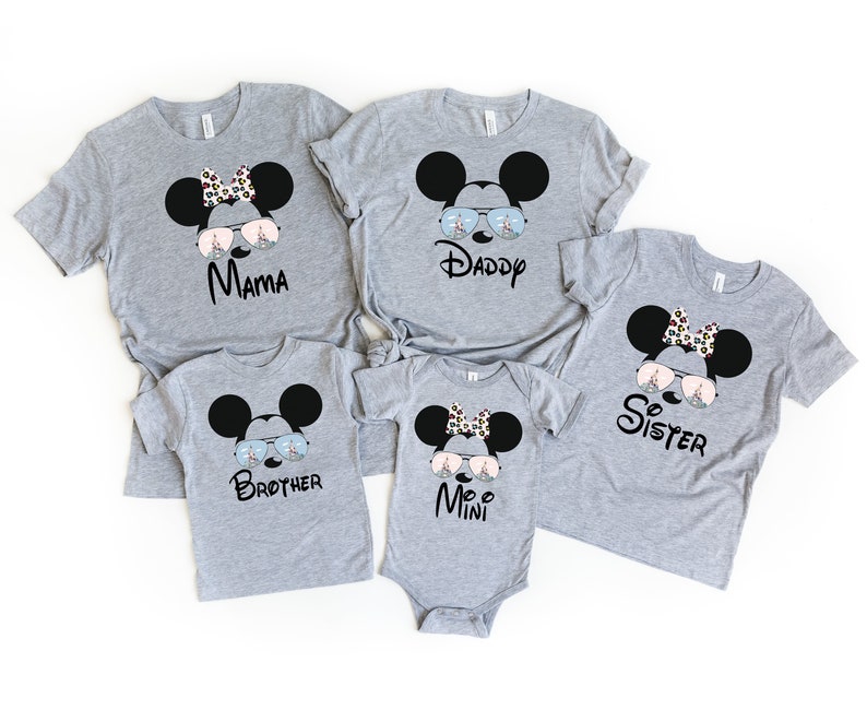 K&ouml;nnte beinhalten: Ein Set aus f&uuml;nf grauen T-Shirts mit einem Cartoon-Bild von Mickey Mouse, der eine Sonnenbrille tr&auml;gt. Die Shirts haben die Worte "Mama", "Daddy", "Sister", "Brother" und "Mini" aufgedruckt.
