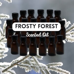 May include: A set of 18 amber glass bottles with black lids, filled with a clear liquid. The bottles are arranged in a semi-circle on a snowy background. The text "FROSTY FOREST Scented Oil" is displayed in white letters on a black rectangle.