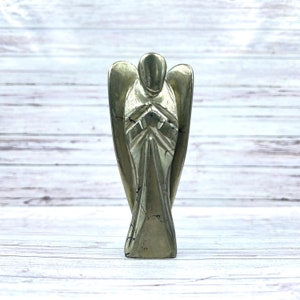 May include: A gold pyrite angel figurine with a detailed design. The angel is standing with its hands clasped in front of its chest.