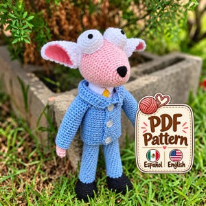 Può includere: Una bambola a forma di pecora all'uncinetto con viso rosa, grandi occhi bianchi e orecchie foderate di rosa, che indossa una giacca da completo azzurra con bottoni bianchi, una camicia bianca e una cravatta gialla. Piedi neri ed etichetta PDF Pattern.