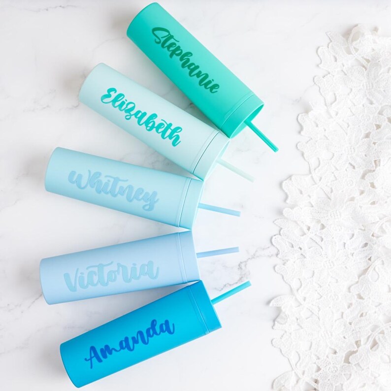 Puede incluir: Cinco vasos personalizados de colores pastel con pajitas. Cada vaso es de un tono diferente de azul y tiene un nombre: Stephanie, Elizabeth, Whitney, Victoria y Amanda. Los vasos est&aacute;n dispuestos sobre una superficie de m&aacute;rmol blanco.