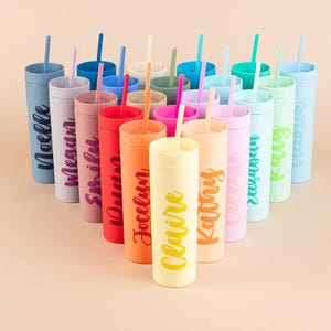 Puede incluir: Una colecci&oacute;n de vasos personalizados y coloridos con pajitas. Cada vaso es de un color diferente, incluyendo azul, rosa, naranja y verde, y presenta un nombre en una fuente de escritura a juego. Los vasos est&aacute;n dispuestos en forma triangular.