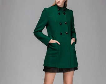 May include: A dark green double-breasted coat with a high collar and black buttons. The coat has two flap pockets and a black mesh skirt underneath.
