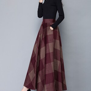 Peut inclure: Une longue jupe &agrave; carreaux bordeaux et marron avec une taille haute et une silhouette &eacute;vas&eacute;e.