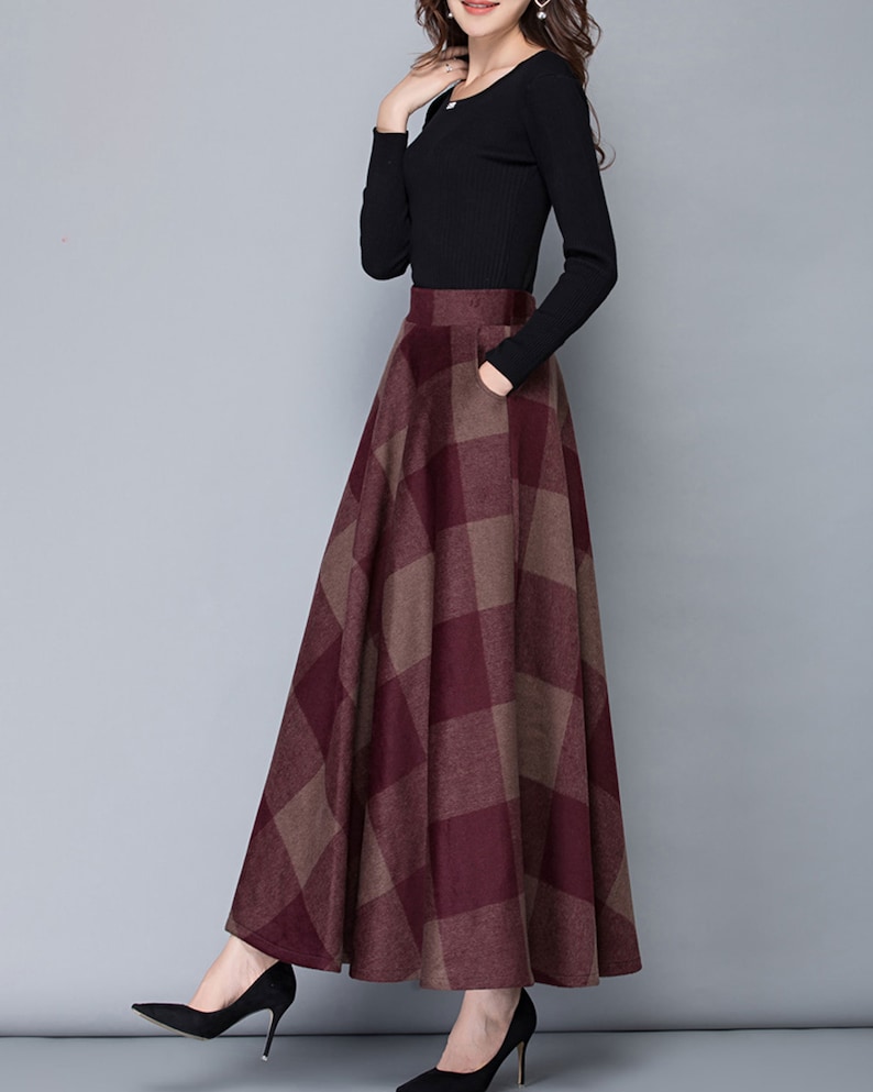 Peut inclure: Une longue jupe &agrave; carreaux bordeaux et marron avec une taille haute et une silhouette &eacute;vas&eacute;e.